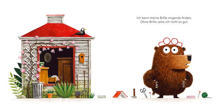 Der Bär steht neben seinem Haus und sagt: Ich kann meine Brille nirgends finden. Ohne Brille sehe ich nicht so gut. Neben ihm liegen viele Dinge aus dem Haus, die bei der Suche schon im Weg waren.